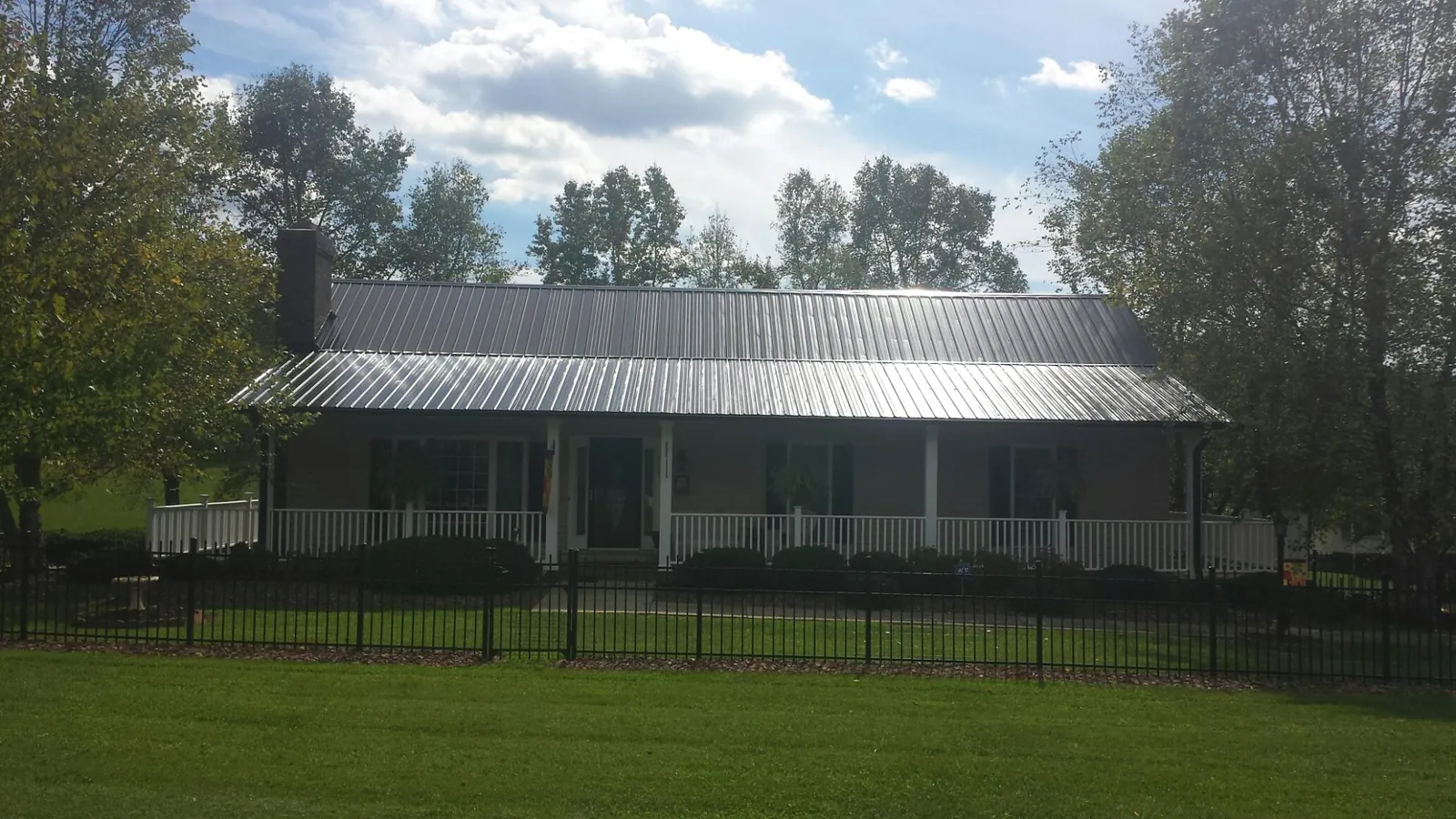 Gray metal roof on a brick ranch with a full width front porch — Gutter Guard Installation work by our crew in East Springfield